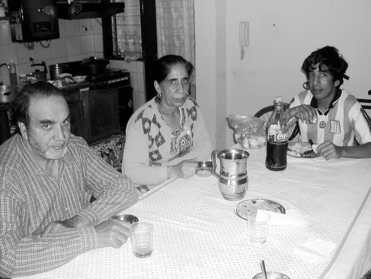 Gurcharan Singh with wife and son wearing Argentine soccer shirt. Parents eating daal roti, son beef steak.